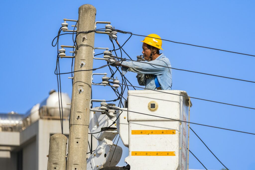 An electrician works on power lines from a lift.